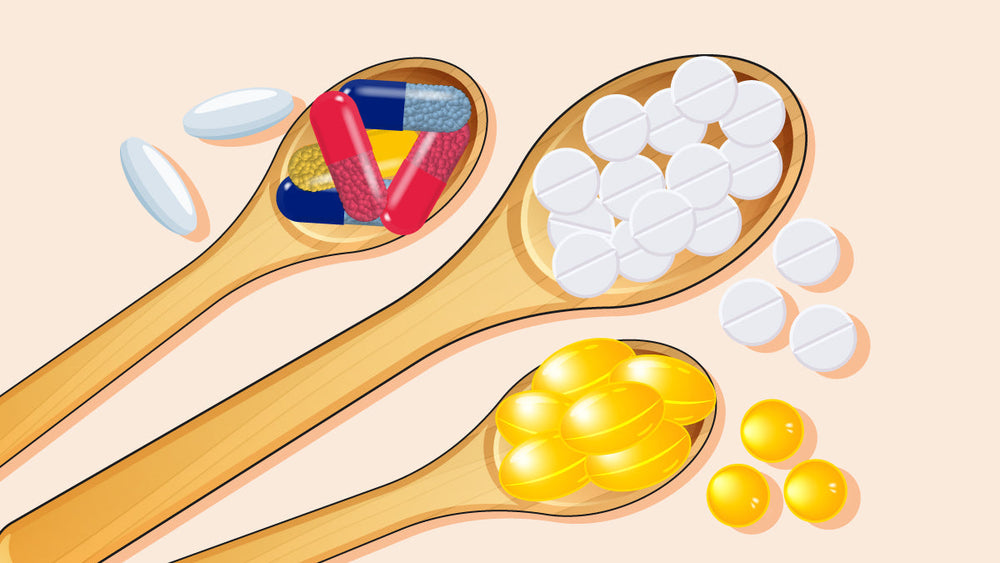 Wooden spoons holding assorted pills, capsules, white tablets, and yellow softgels.