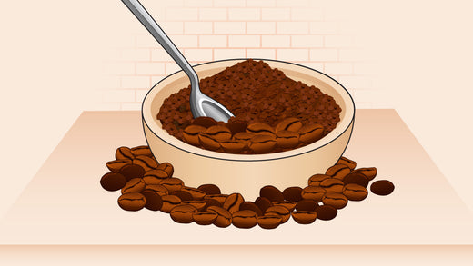 Bowl of ground coffee with a spoon inside, surrounded by scattered roasted coffee beans
