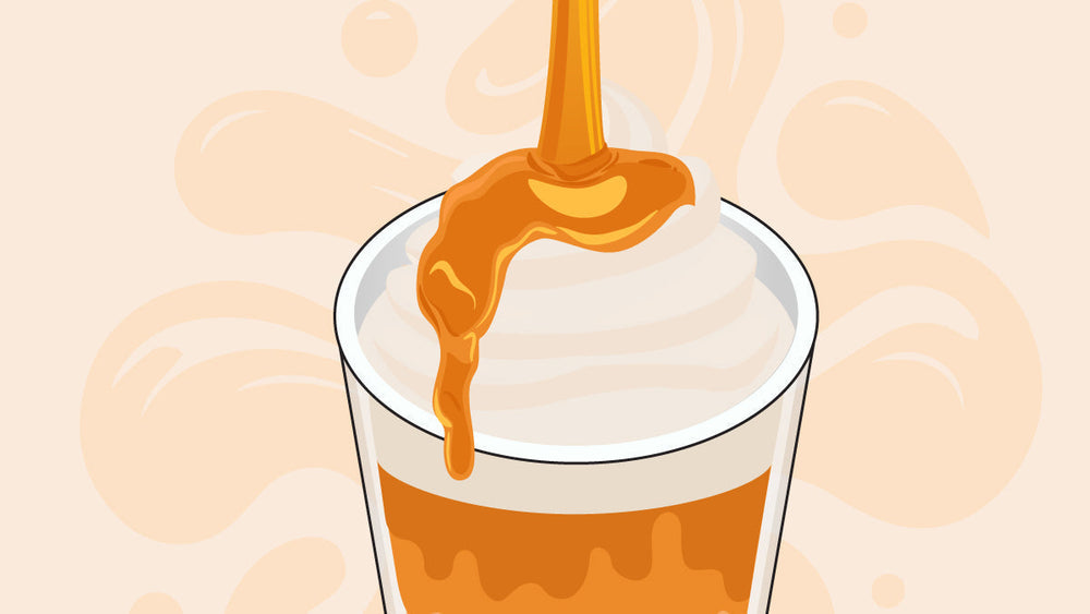 Caramel syrup being poured over whipped cream on top of a caramel drink in a glass.