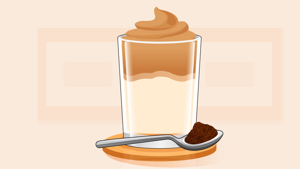 Whipped coffee in a glass with a spoonful of instant coffee on the side.