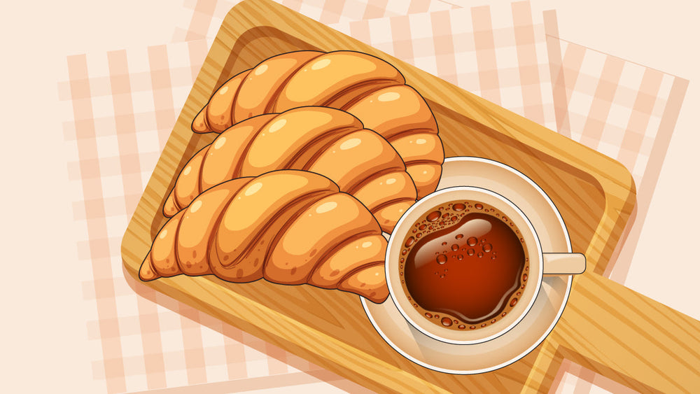 Three croissants on a wooden tray beside a cup of coffee on a checkered cloth.