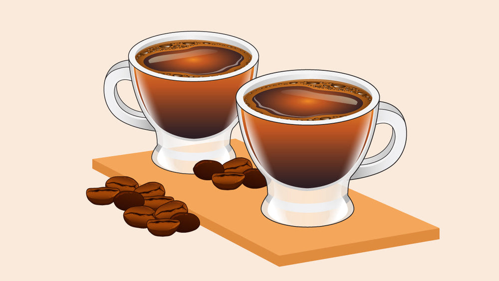 Two cups of Cuban coffee with a foamy top layer, placed on a wooden board with scattered coffee beans.