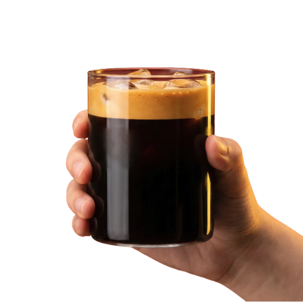 A hand holding a glass of dark Vietnamese coffee with a thick crema